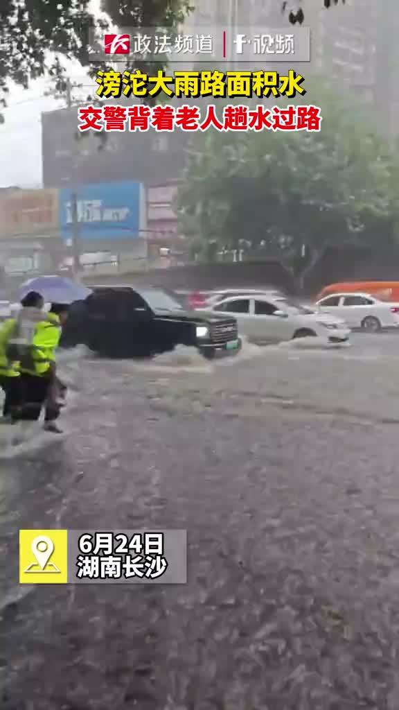 滂沱大雨路面积水交警背着老人趟水过路